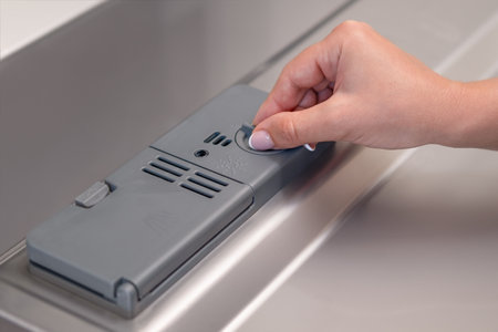 female hand puts dishwasher tablet into open automatic built-in dishwasher machine. Close up.の写真素材