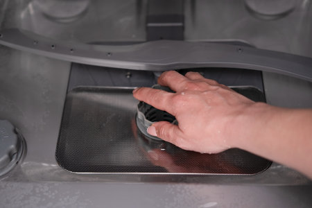 woman's hand checking the filter in the dishwasher.の写真素材