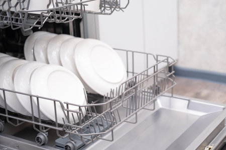 Built-in dishwasher door open. Kitchen with built-in appliances. Plates and dishes are dishwasher safe.の写真素材
