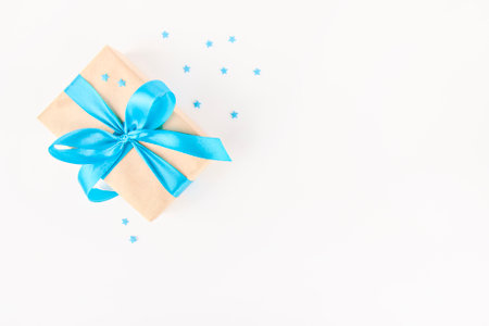 on a light background a gift with a blue ribbon, a fir branch and blue ornaments.の写真素材