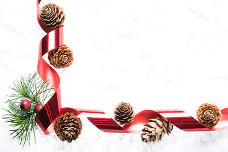 seasonal border made with larch cones, pine, crataegus berries and red ribbon on white backgroundの写真素材