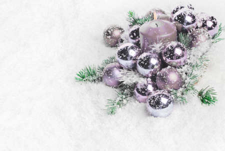 Purple Christmas baubles and candle on snow. With copy space on the leftの写真素材