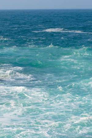 Blue sky and sea with white foam in vertical compositionの写真素材