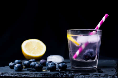 Infused detox water with blueberries and lemon on black background. Refreshment summer drink.の写真素材