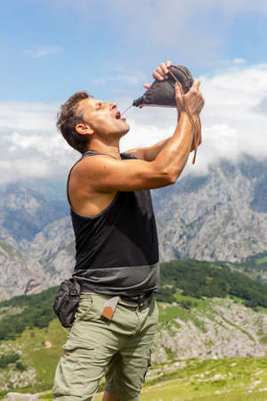 Man drinking red wine from a wineskin in the mountains.Picos de Europa. Spainの写真素材
