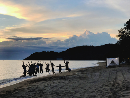 Silhouette beach with jumping group of peopleの写真素材
