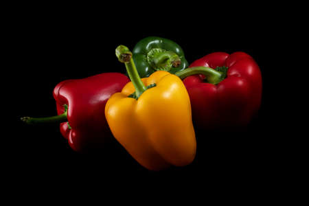Three, sweet colorful peppers on a black background. Three colors of sweet pepper. Bell paprika red, green and yellow.の写真素材
