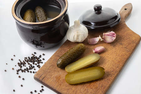 Pickled cucumbers in a stone dish.  Sliced cucumbers on a wooden board.. White background. Polish cuisine. Tastes of Europe. Healthy food.の写真素材