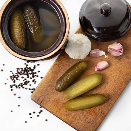 Pickled cucumbers in a stone dish.  Sliced cucumbers on a wooden board.. White background. Polish cuisine. Tastes of Europe. Healthy food.の写真素材