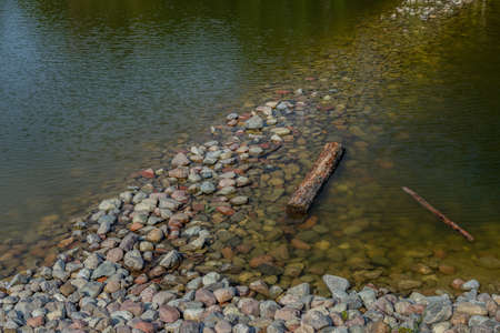 Stones in the water. The rocky shore of the pond. Resting at the lake. Holiday hiking. Europe, Poland, Mazovia.の写真素材