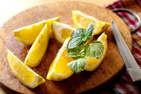 Mint with lemon on a wooden board with a knife. Fresh citruses. Sliced lemon.の写真素材