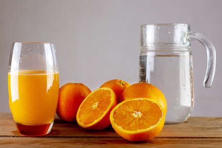 Oranges on a wooden table. A jug of water and a glass of juice. Fresh, squeezed orange juice.の写真素材