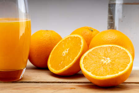 Oranges on a wooden table. A jug of water and a glass of juice. Fresh, squeezed orange juice.の写真素材