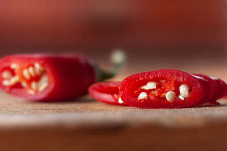 Sliced red chili hot pepper on a wooden board. Spicy foods. Vegetable seeds..の写真素材