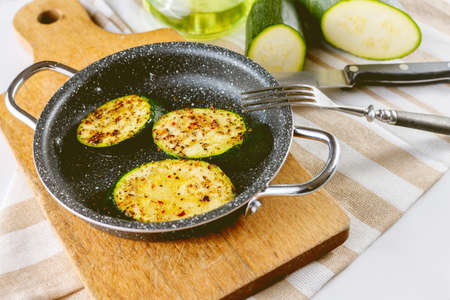 Zucchini snack in a small pan. Zucchini table. Vegan snack. Wooden chopping board. Old cutlery.の写真素材