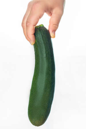 Hand with zucchini on a white background. Woman with zucchini in hand. Vegan cuisine. Healthy vegetables.の写真素材