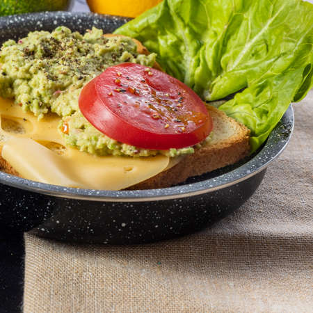 Toast with avocado, cheese and tomato. Breakfast sandwich. Preparation of a healthy breakfast. Lettuce, onions, garlic and avocado. Breakfast time.の写真素材