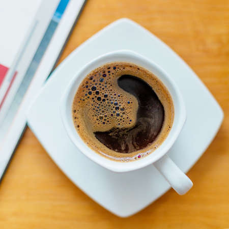 White cup of black coffee. A cup of hot drink on a wooden table. A coffee break. Relax time.の写真素材
