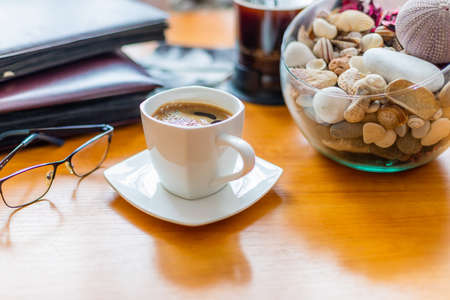 Time for reflection over coffee. White cup. Prescription glasses. Decoration with shells and stones. Black coffeeの写真素材