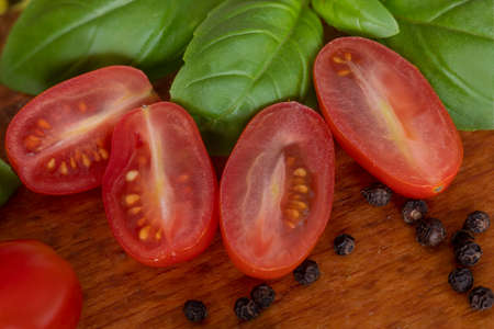Tomatoes with basil and pepper. A wooden board in the background. Tastes of Italy. Tomato salad.の写真素材