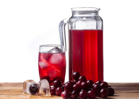 Cherry compote in a jug. Cherries on a wooden table. Ice cubes. A cold fruit drink in a glass.の写真素材