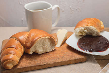 Croissant with coffee, chocolate, tea for breakfast. Rustic table in the morning. Plum jam for breads. Rural leisure.の写真素材
