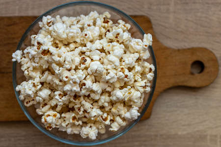 Popcorn in a glass bowl. Processed corn. Snack to the movie. In the cinema. Before the movie.の写真素材