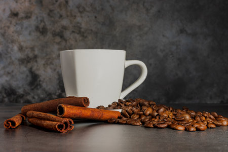 White cup, cinnamon and coffee beans on a gray background. Morning coffee. Coffee shop menu.の写真素材
