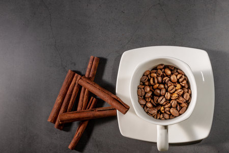 White cup, cinnamon and coffee beans on a gray background. Morning coffee. Coffee shop menu.の写真素材