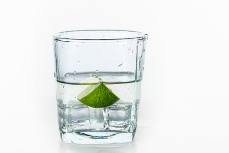 Glass of water with lime and ice on white background, refreshing drinkの写真素材