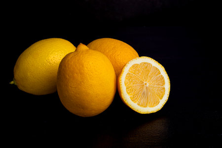 Three and a half lemons on a black background. Healthy eating. Citrus in the kitchen.の写真素材