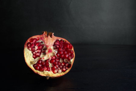 Half of a pomegranate on a black background. Healthy food. Tropical fruits.の写真素材