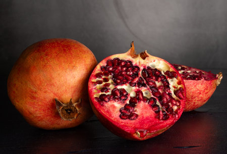 Pomegranate fruits on a graphite background. Fruit cross-section. Healthy food. Tropical fruits