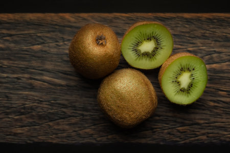 Whole and cut kiwi on a wooden brown table. Green fruits. Vitamin C. Fruits in the kitchen.の写真素材