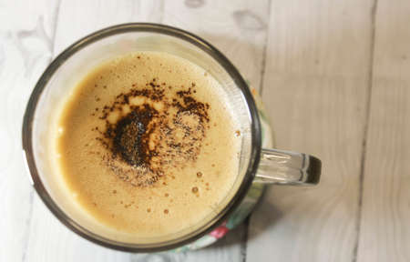 Photo of cappuccino coffee in a clear glass cup on a wooden tableの写真素材