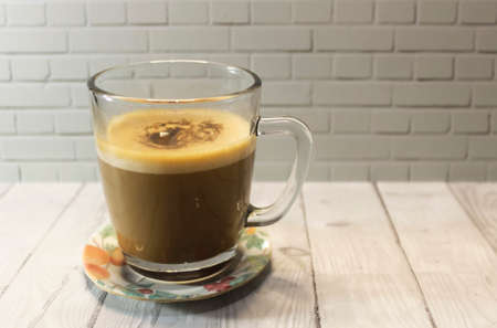 Photo of cappuccino coffee in a clear glass cup on a wooden tableの写真素材
