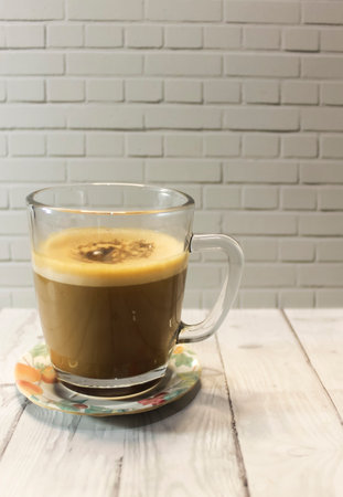 Photo of cappuccino coffee in a clear glass cup on a wooden tableの写真素材