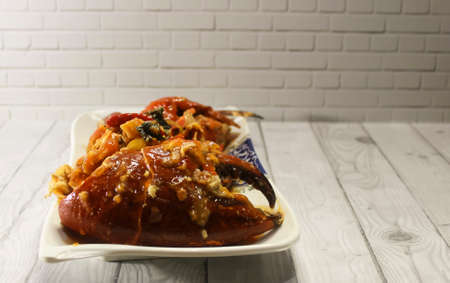 Photo of A plate of crab cooked in sauce on a wooden patterned tableの写真素材