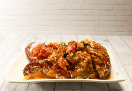 Photo of A plate of crab cooked in sauce on a wooden patterned table