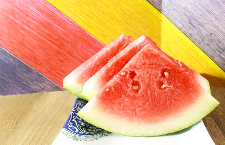 Photo of three fresh red watermelon slices on a wooden patterned tableの写真素材