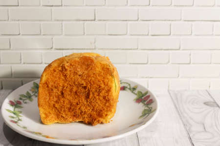 Photo of a shredded bread roll on a white plate on a wooden tableの写真素材