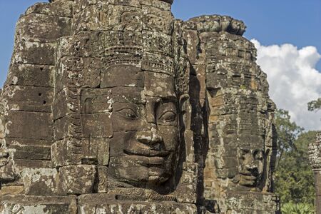Buddha's stone faceat sunny day in ancient temple of Angkor Wat with blue sky. Siem Reap. Cambodia.の写真素材