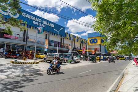 Moalboal. Cebu. Philippines - 03 april 2016: Mall Gaisano under blue sky near parking and road with motorcycle, bus and tricycleのeditorial素材