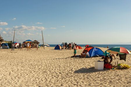 Moalboal.Cebu.Philippines - 06 april 2016: Philippine people with tents and ambrella getting rest and playing volleyball on the white bechのeditorial素材