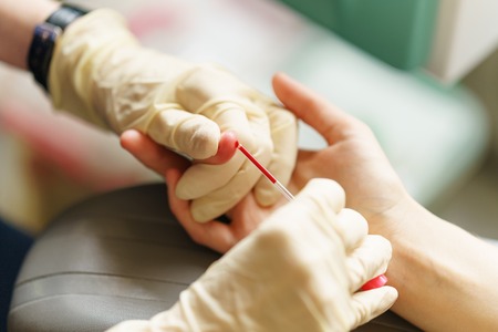 medical nurse with latex gloves is taking patient's blood for analysis at day timeの写真素材