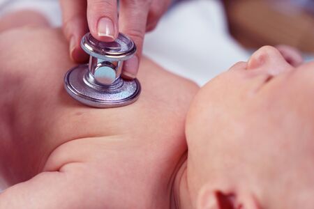 Doctor listening heartbeat of newborn baby by stethoscope at day time