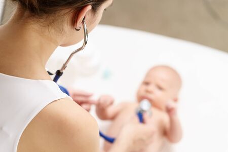 Doctor listening heartbeat of newborn baby by stethoscope at day timeの写真素材