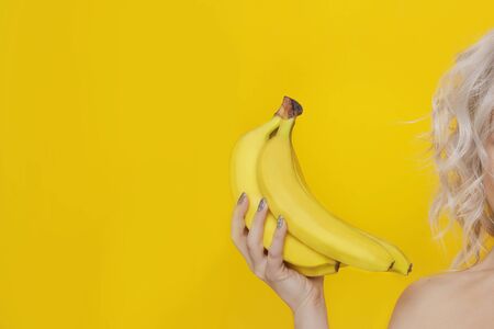 Bananas in woman hands on yellow backgroundの写真素材