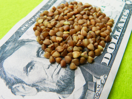 Close up photo of a buckwheat grain on the five-year banknote on the green background illustrated the high prices of the buckwheatの写真素材