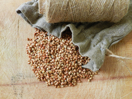 Buckwheat groat with sac and twine knot on the wooden table close upの写真素材